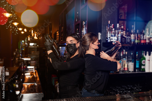 Latina prepares a cocktail at a bar counter. job waitress profession
