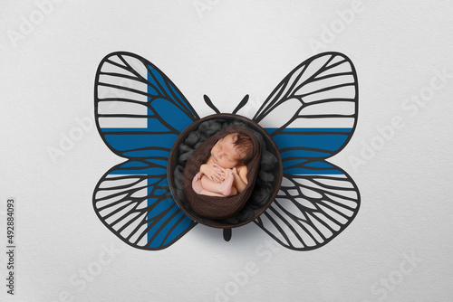 Tiny baby portrait with wings in color of national flag. Newborn photography concept. Finland