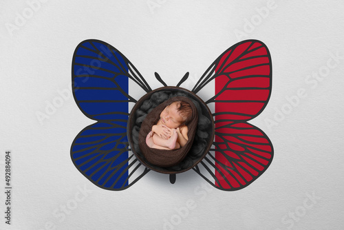 Tiny baby portrait with wings in color of national flag. Newborn photography concept. France