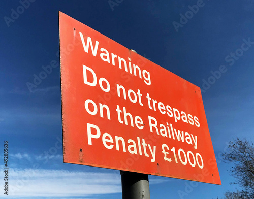 Sign alongside railway tracks warning tresspassers of finanical penalty fines. No people. photo