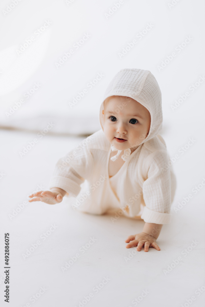 Cute studio portrait of a little newborn girl posing for a photo on a light background. A baby who has already learned to crawl and sit Cute studio portrait of a little newborn girl posing for a photo on a light background. A baby who has already learned to crawl and sit