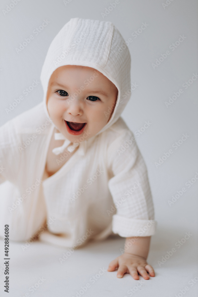 Cute studio portrait of a little newborn which has already begun to crawl. The child laughs and rejoices in his first little steps Cute studio portrait of a little newborn which has already begun to crawl. The child laughs and rejoices in his first little steps
