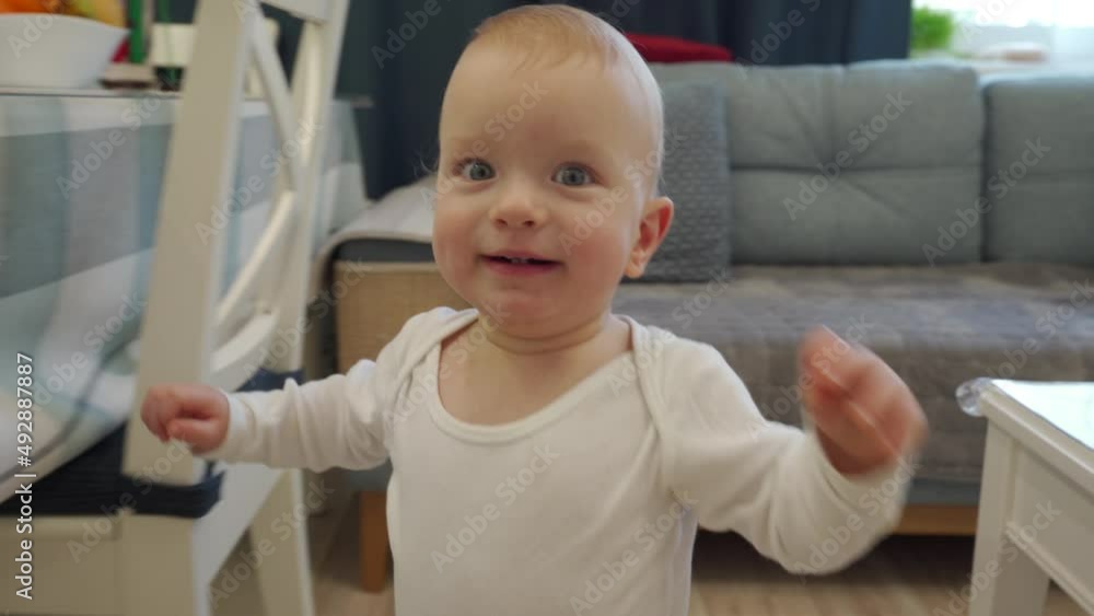 1 year old baby boy learning to walk in the living room, toddler exploring home curious infant walking through house, child looking at camera. High quality 4k footage 1 year old baby boy learning to walk in the living room, toddler exploring home curious infant walking through house, child looking at camera. High quality 4k footage