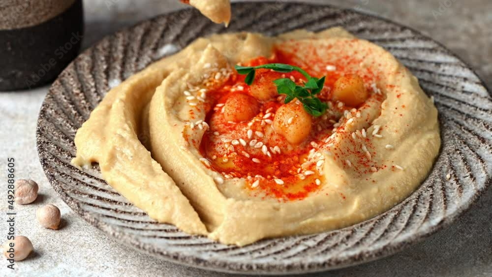 Eating hummus with crispbread. hummus with sesame, olive oil and paprika. Healthy vegan food. Vegetarian dish. Mezze chickpeas. Kosher food. Eating hummus with crispbread. hummus with sesame, olive oil and paprika. Healthy vegan food. Vegetarian dish. Mezze chickpeas. Kosher food.