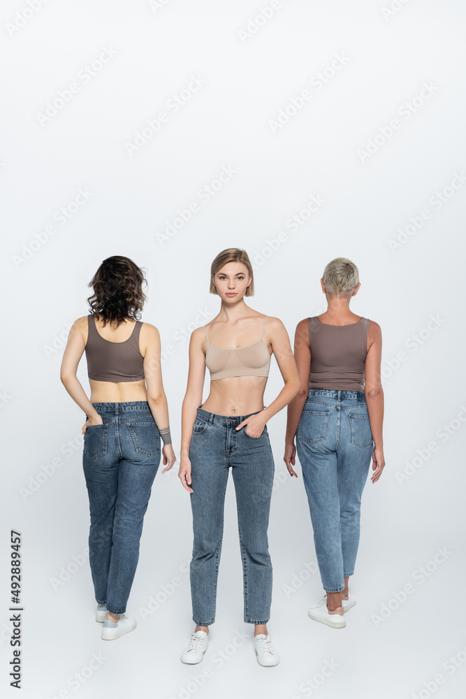 Young blonde woman posing near friends on grey background. Young blonde woman posing near friends on grey background.