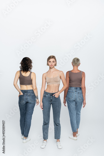 Young blonde woman posing near friends on grey background.