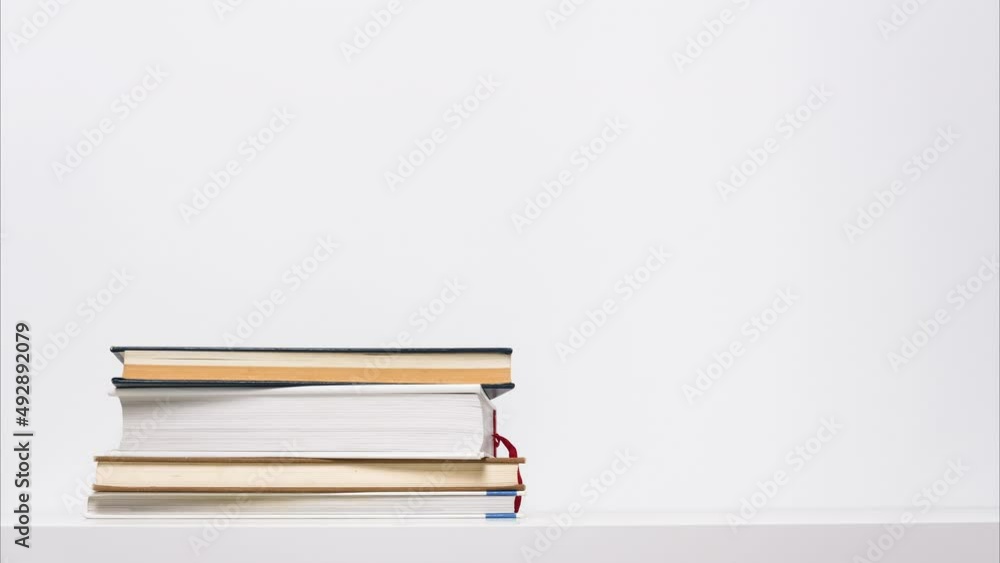 Stop motion animation of growing and shrinking stack of books isolated on white background. Educational or learning concept. Stop motion animation of growing and shrinking stack of books isolated on white background. Educational or learning concept.