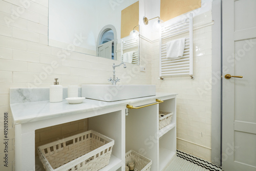 bathroom with white porcelain fixtures  white tile walls and black and white tile floors  white towel radiator  gray marble countertop and mirror