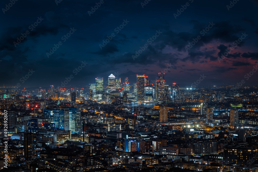 Elevated view over the illuminated skyline of London during night time until the financial district Canary Wharf, England