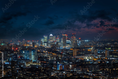 Elevated view over the illuminated skyline of London during night time until the financial district Canary Wharf, England
