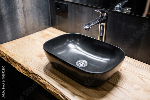 new stylish and modern black sink with water tap on wooden countertops