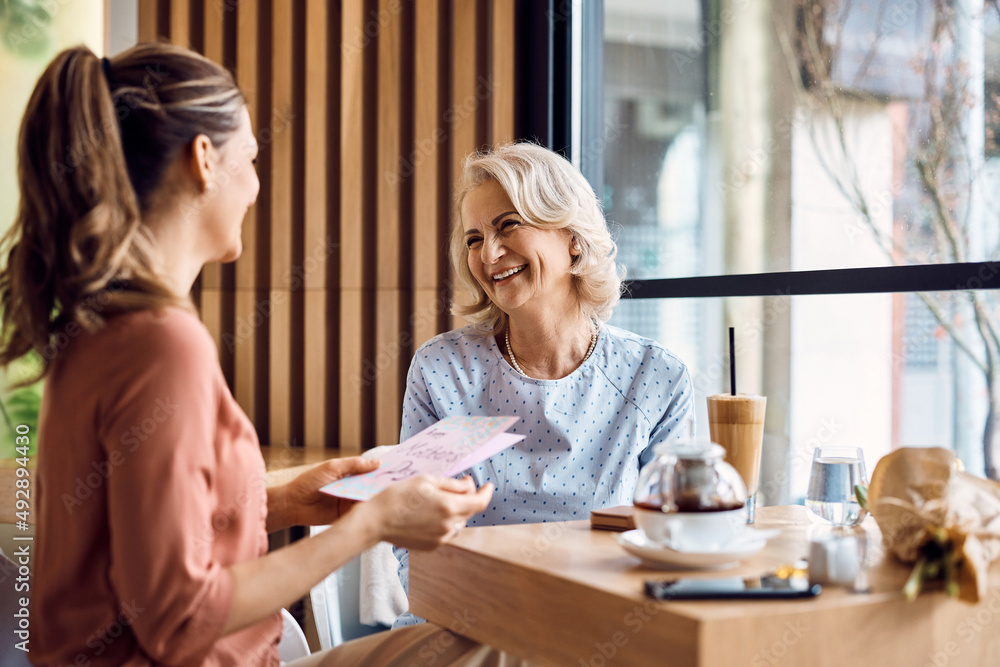 Happy senior woman and her daughter talking while celebrating mother's day in cafe. Happy senior woman and her daughter talking while celebrating mother's day in cafe.