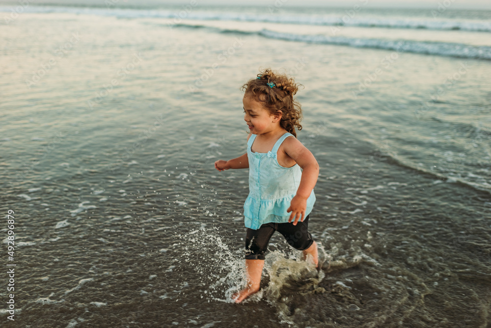 Young girl running through the surf at sunset Young girl running through the surf at sunset