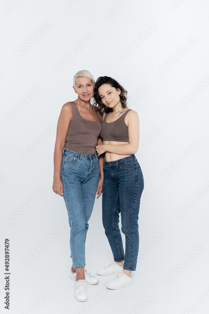 Smiling women looking at camera on grey background, feminism concept. Smiling women looking at camera on grey background, feminism concept.