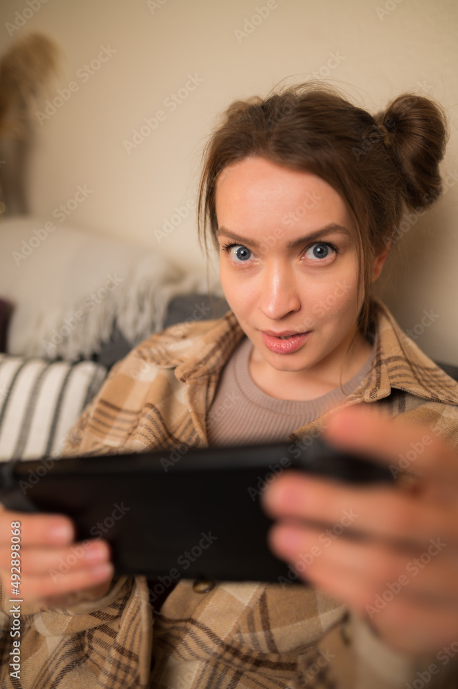 Player plays on portable console, young girl with smile plays on portable console.Concept of cyberprot, entertainment for children, computer games Player plays on portable console, young girl with smile plays on portable console.Concept of cyberprot, entertainment for children, computer games