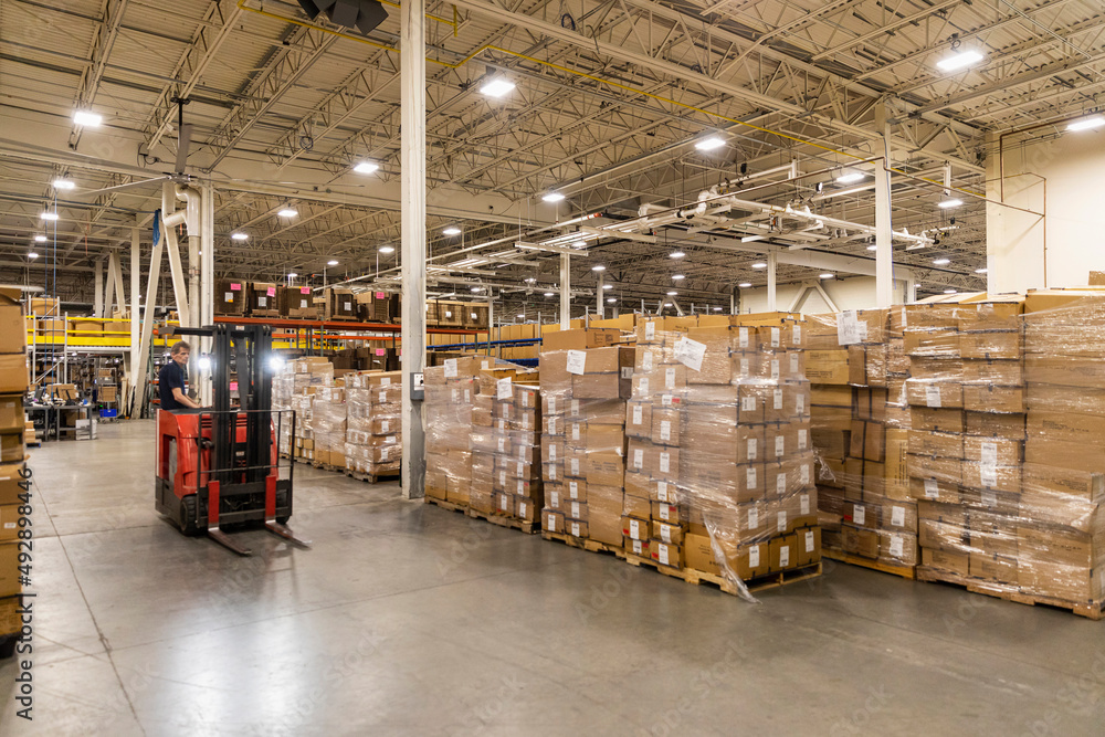 Forklift driver moving through warehouse Forklift driver moving through warehouse