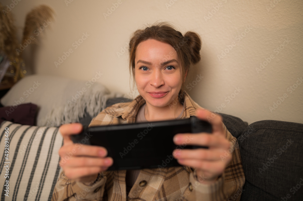 Young girl plays games on console, portable console in games online.Concept player, eSports, gaming business. Advertising of games for consoles, conrollers or josticks, online games and sale Young girl plays games on console, portable console in games online.Concept player, eSports, gaming business. Advertising of games for consoles, conrollers or josticks, online games and sale