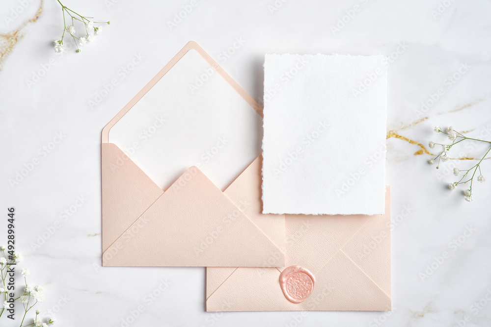 Blank white invitation cards with pink envelopes and gypsophila branches on marble table. Wedding stationery set. Flat lay, top view, copy space. Blank white invitation cards with pink envelopes and gypsophila branches on marble table. Wedding stationery set. Flat lay, top view, copy space.
