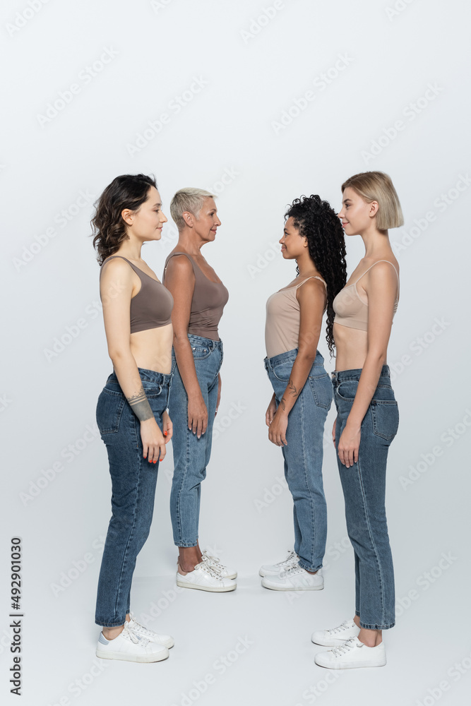Side view of interracial women looking at each other on grey background. Side view of interracial women looking at each other on grey background.