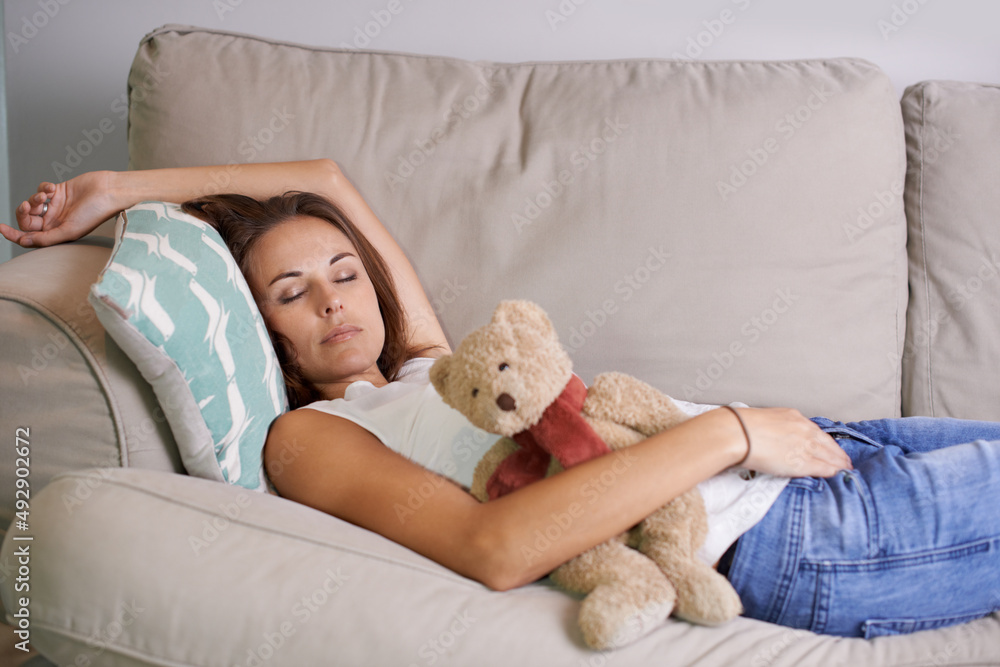 Even mom sometimes needs a nap. Exhausted young mother fast asleep on the sofa with her childs teddy bear in hand. Even mom sometimes needs a nap. Exhausted young mother fast asleep on the sofa with her childs teddy bear in hand.