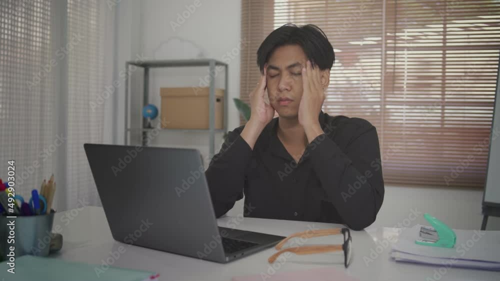 Asian man feeling stress from work in the office.The dismissed company employee was sad. He was so stressed that he fell on his desk. Asian man feeling stress from work in the office.The dismissed company employee was sad. He was so stressed that he fell on his desk.