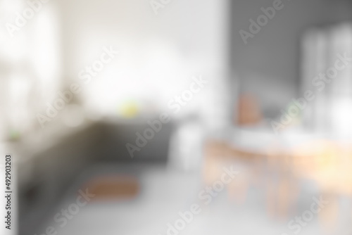 Blurred view of modern kitchen with counters and dining table