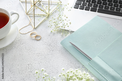Stylish notebook with jewelry, gypsophila flowers and laptop on grunge background, closeup
