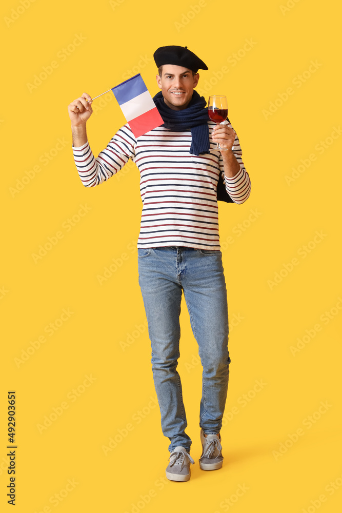 Handsome young man with flag of France and wine on yellow background Handsome young man with flag of France and wine on yellow background