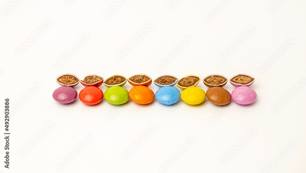 Candies of different colors are laid out in the middle on a white background. Chocolate halves cut in half. Delicacies for children. Candies of different colors are laid out in the middle on a white background. Chocolate halves cut in half. Delicacies for children.