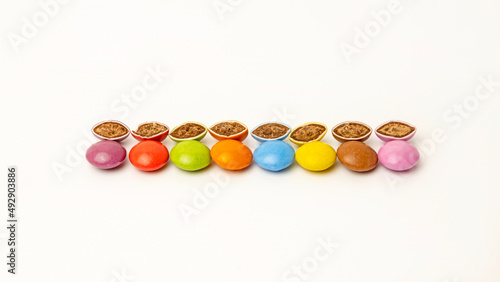 Candies of different colors are laid out in the middle on a white background. Chocolate halves cut in half. Delicacies for children.