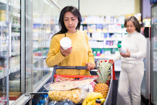 Female shopper chooses dairy products at grocery supermarket