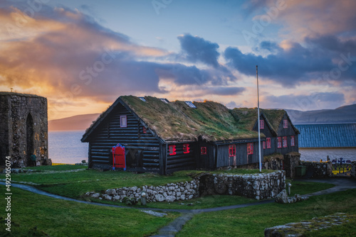 Old log farmhouse of Kirkjuboargardur with turf roof in Kirkjubour village on Streymoy, Faroe Islands. Sunrise time, november 2021 photo