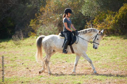Enjoying a quiet horse ride. A young woman riding her horse. © Marine G/peopleimages.com