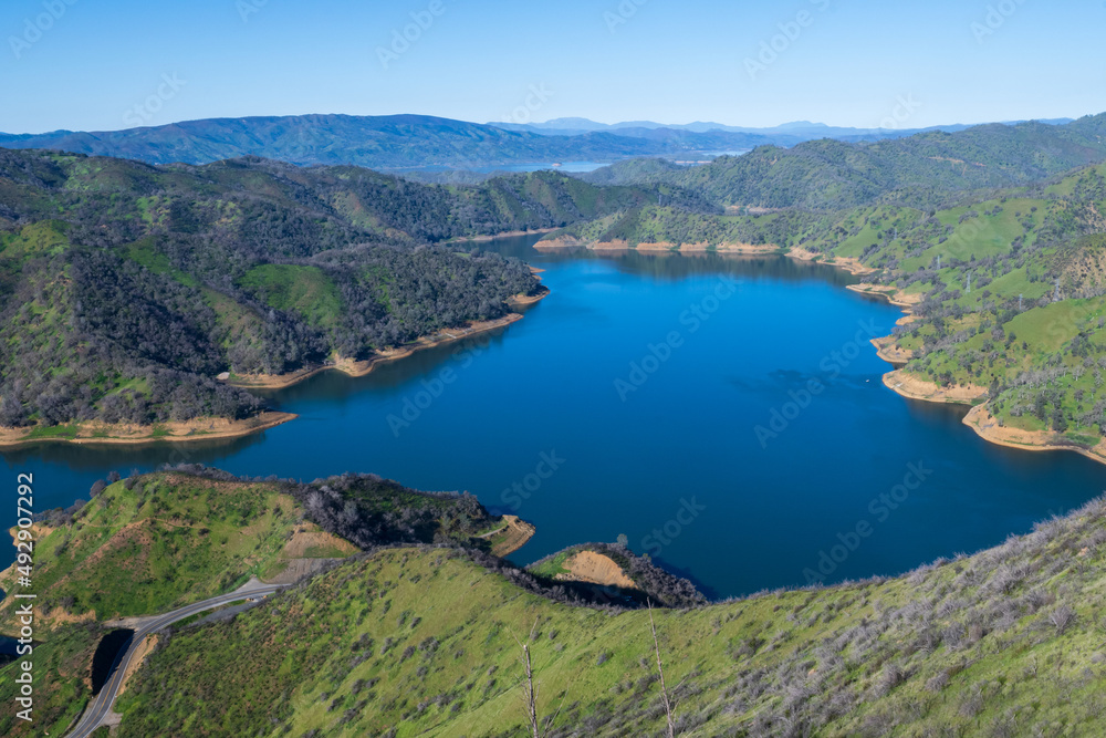 Aerial vew of Lake Berryessa from the Blue Ridge Trail on a sunny day, featuring the reservour and the surrounding blue oak woodland