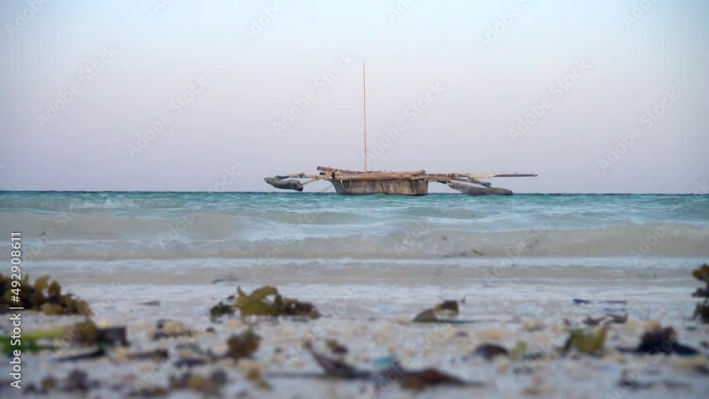 Zanzibar traditional old wooden boat in the water anchored near the beach. Low view point.