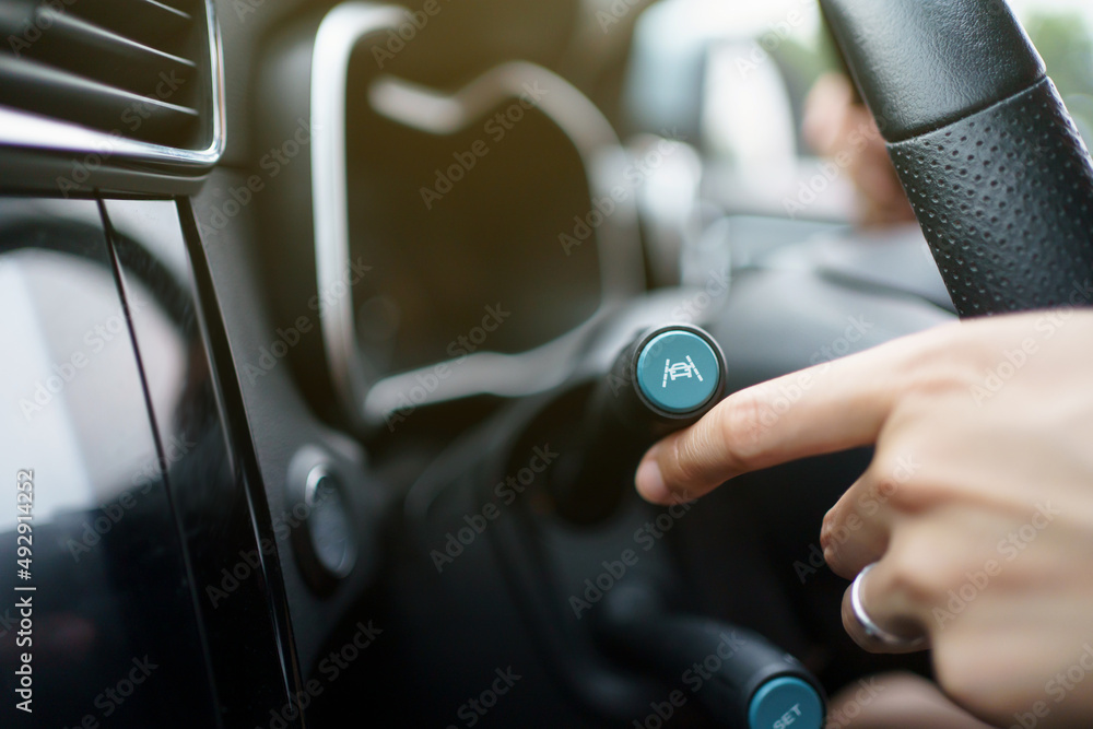 Unrecognizable woman driver activating the adaptive cruise control or steering assistant.