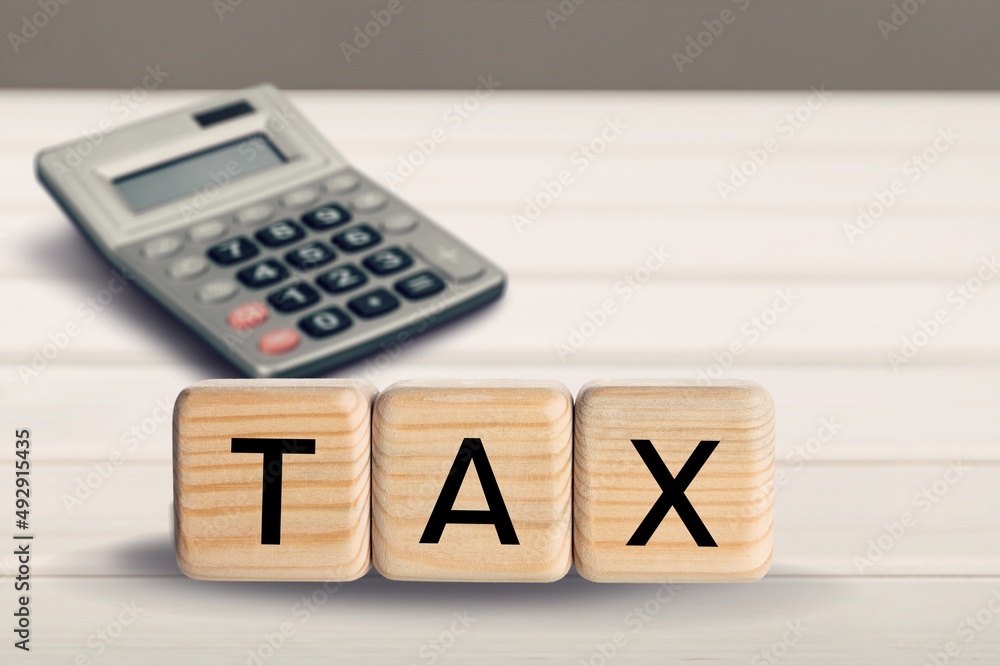 Concept of tax calculation calculator and the word “TAX†on wooden cube Concept of tax calculation calculator and the word “TAX†on wooden cube