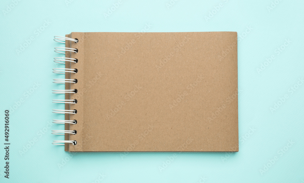 Notebook with brown paper pages on light blue background, top view Notebook with brown paper pages on light blue background, top view