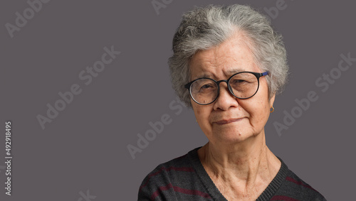 Portrait of a senior woman with short gray hair looking at the camera with a smile while standing on gray background