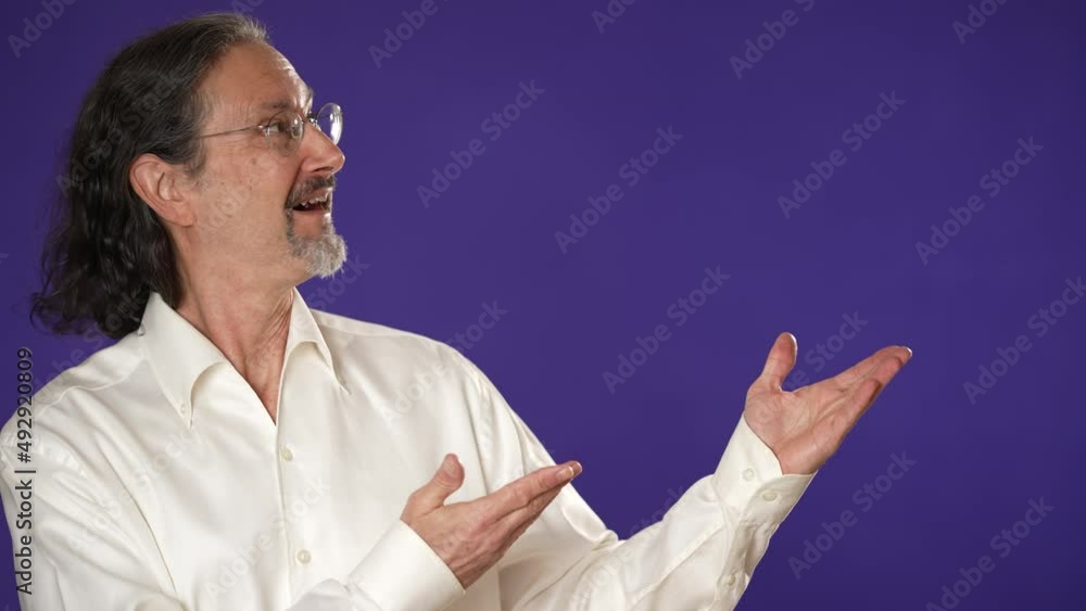 Excited promoter businessman 50s 60s white shirt point fingers aside on copy space blank mockup promo commercial area isolated on solid purple background studio portrait Excited promoter businessman 50s 60s white shirt point fingers aside on copy space blank mockup promo commercial area isolated on solid purple background studio portrait