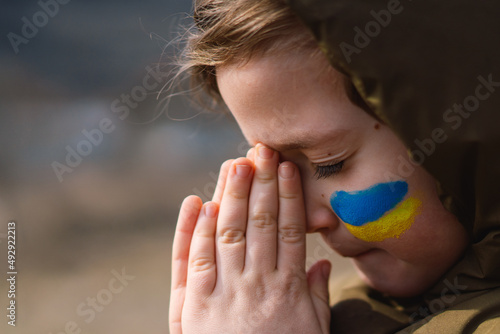 Ukrainian boy closed her eyes and praying to stop the war in Ukraine. Hands folded in prayer concept for faith, spirituality and religion. War of Russia against Ukraine. Stop War