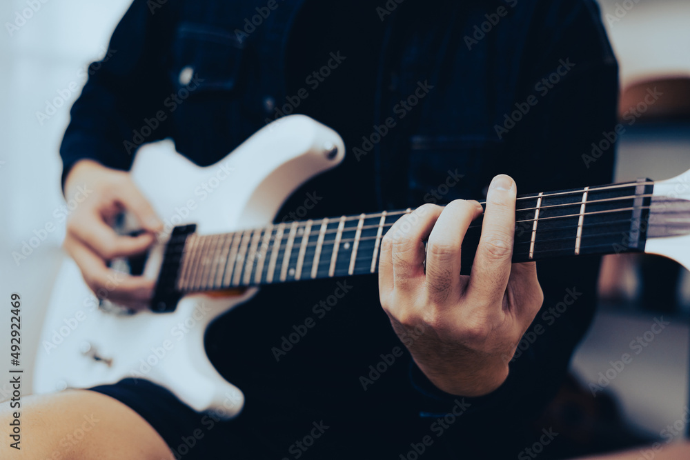 Close up hands young man rocker playing electric guitar at home In the morning. Young man practicing heavy metal music and solo guitar