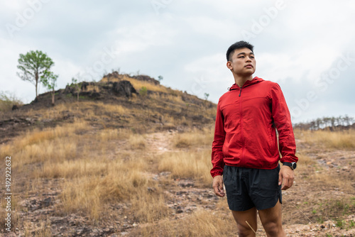 Young handsome asian Trail runner man standing on top of the mountain. Athlete jog outdoor for healthy. Confident and powerful marathon man running workout and cardio. Sport and Lifestyle concept. © Chanakon