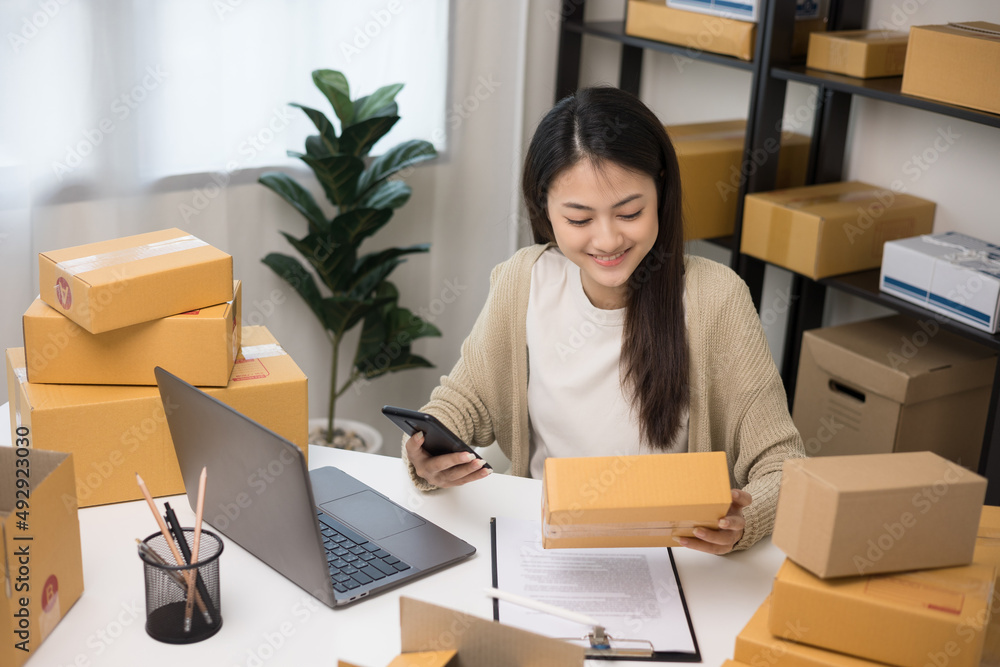 Startup Small business owner entrepreneur. Young asian business woman using mobile phone call receiving purchase order and check product on stock. E-commerce business and shopping online concept. Startup Small business owner entrepreneur. Young asian business woman using mobile phone call receiving purchase order and check product on stock. E-commerce business and shopping online concept.