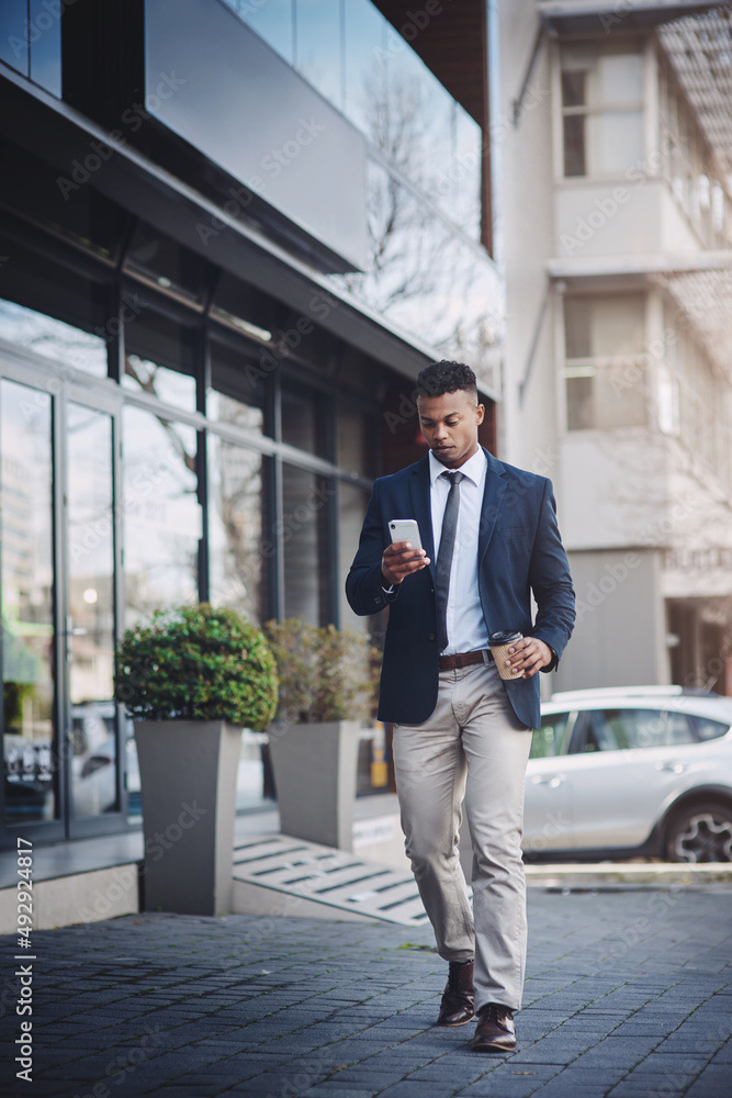 Catching a quick coffee before heading back. Shot of a handsome young businessman using a cellphone in the city.