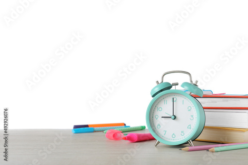 Turquoise alarm clock and different stationery on wooden table against white background, space for text. School time