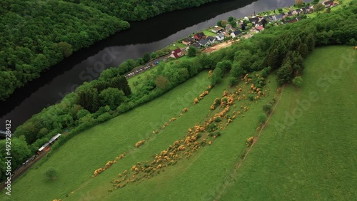 Small village next to river with dark reflecting waters and green hills photo