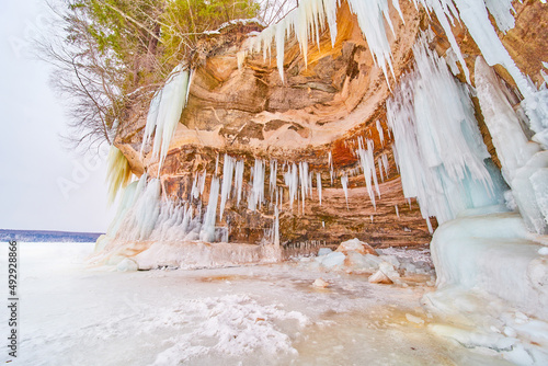 Wavy cliff cave on frozen lake covered in pointed icicles