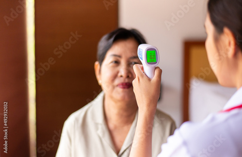 Doctor checking temperature with thermometer to middle aged adult women Home care doctor service
