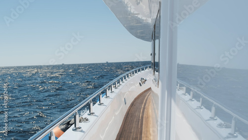 White yacht deck sailing on sea waves on sunny day  close-up. Sea voyage on luxury yacht. Clear blue sky above horizon. Concept of success  travel cruise  lifestyle  freedom. No people